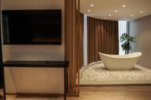 uma sala de estar com uma televisão e uma banheira em BAZ'HUR Boutique Hotel em Kukës
