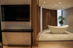 a living room with a tv and a bath tub at BAZ'HUR Boutique Hotel in Kukës