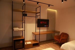 um quarto com uma cama, uma televisão e uma cadeira em BAZ'HUR Boutique Hotel em Kukës