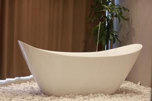 una bañera blanca sentada en una mesa con una planta en BAZ'HUR Boutique Hotel, en Kukës