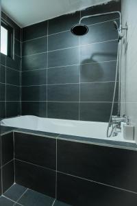 y baño con bañera y azulejos negros. en Cosy City-View Suite in Town, en Ipoh