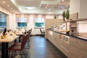 a restaurant with tables and chairs and a kitchen at Hotel Am Freischütz in Hürth