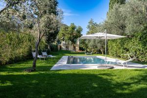 a pool with an umbrella and a chair and a table and an umbrella at Villa Lilla Bellagio - Pool and Wine with Lake view in Bellagio