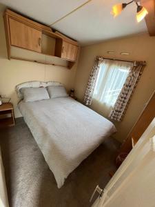 een groot bed in een kleine kamer met een raam bij Tregoodwell Park Lodge in Camelford