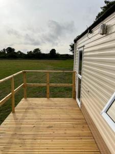 een houten terras naast een gebouw met een veld bij Tregoodwell Park Lodge in Camelford