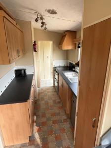 a small kitchen with wooden cabinets and black counter tops at Tregoodwell Park Lodge in Camelford
