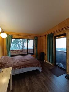 a bedroom with a bed and a large window at Янтарь Уютный горный домик in Almaty