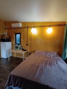 a bedroom with a bed and a table and two lights at Янтарь Уютный горный домик in Almaty