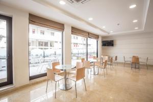 a dining room with tables and chairs and windows at Hotel Roxy & Beach in Cesenatico