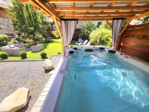 a swimming pool in a backyard with a pergola at Le Cosy Lodge Départs Vélo Ski Alpe d'Huez 2 Alpes La Grave Détente Jacuzzi Piscine Sauna Bar Billard in Le Bourg-dʼOisans