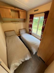 a small room with two beds and a window at Tregoodwell Park Lodge in Camelford