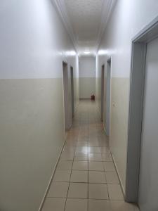 an empty hallway with doors and a tile floor at Romo Cocotier in Cotonou