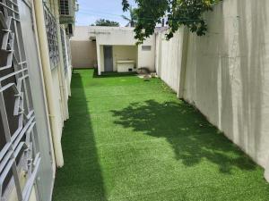an alley with green grass between two buildings at Romo Cocotier in Cotonou