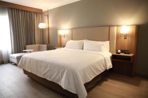 una habitación de hotel con una cama grande con sábanas blancas en Holiday Inn Durango, an IHG Hotel, en Durango