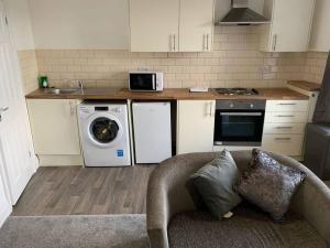 a kitchen with a washing machine and a microwave at Modern Town Centre Apartment in Neath in Neath