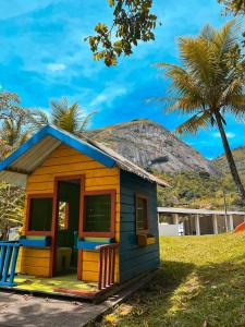 a small yellow and blue house with a palm tree at Apt Flat 210 Condomínio Pedra do Rodeadouro in Bonito