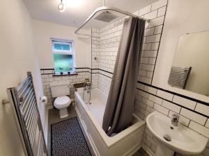 a bathroom with a tub and a toilet and a sink at 5 bedroom, recently renovated house close to Hastings Beach in Hastings +17 photos