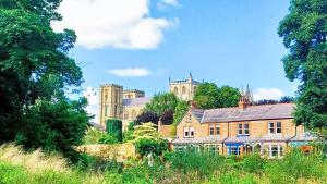 a large brick building with a castle in the background at Cosy Retreat - house with double bedroom in Ripon