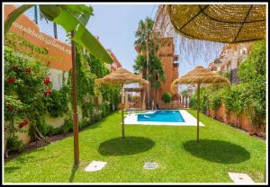 una piscina con sombrillas en el césped junto a un edificio en Villas Cañada, en Torrox Costa