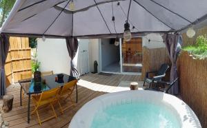 a patio with a hot tub and a table and chairs at L'Entre-Nous Carcassonne in Carcassonne