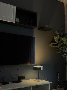 un televisor en una pared con una mesa con una lámpara en Dream Central Appartment, en Tesalónica