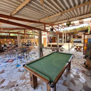 a pool table in a room with tables and chairs at Diógenes Pousada in Conceição da Ibitipoca