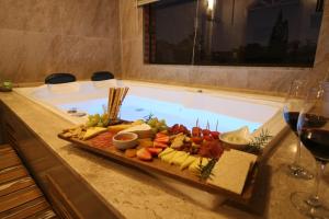 プライア・ド・ローザにあるPousada Sunsetの浴槽の横のテーブルに食料品を並べたトレイ