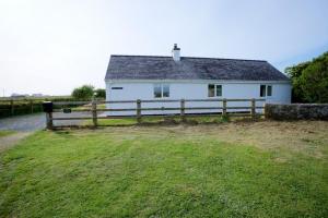 a white house with a fence in a field at Hideaway in Rhosneigr