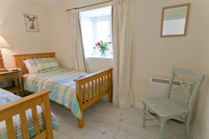 a bedroom with a bed and a chair and a window at Hideaway in Rhosneigr