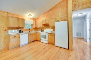 Una cocina con gabinetes de madera y un refrigerador blanco. en Mtn View and Fire Pit Pet-Friendly Woodlawn Cabin!, en Woodlawn