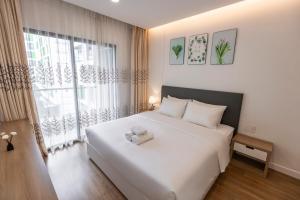 a bedroom with a white bed and a large window at Republic Apartments Saigon Airport in Ho Chi Minh City