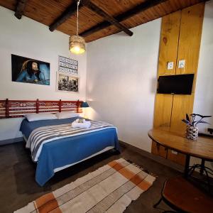 1 dormitorio con cama, mesa y TV en Diógenes Pousada en Conceição da Ibitipoca