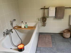 La salle de bains est pourvue d'une baignoire avec bougie et d'un lavabo. dans l'établissement L'Ancienne Forge - Gîte à la ferme, à Sainte-Marie