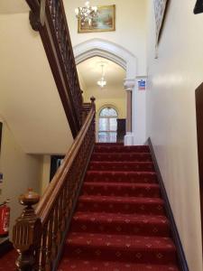 uma escada com uma carpete vermelha e um estojo de escadas em The Lismore Hotel em Banbury