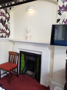 a room with a fireplace with a chair and a tv at The Lismore Hotel in Banbury