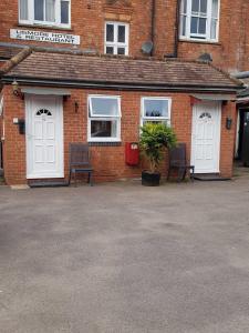 a brick building with two white doors and two benches at The Lismore Hotel in Banbury