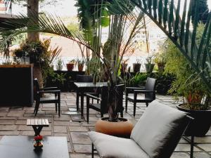 une terrasse avec un canapé, des tables et des plantes dans l'établissement La Varangue, à Antananarivo