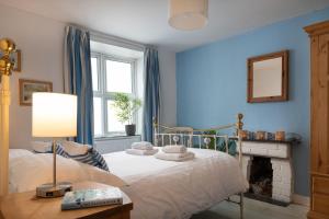 - une chambre bleue avec un lit et une cheminée dans l'établissement Glandwr, à Rhosneigr