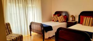 een slaapkamer met 2 bedden, een stoel en een raam bij Casa dos Limões in Caldas da Rainha