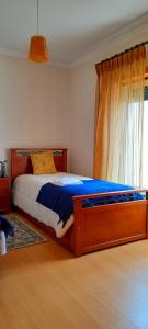 Schlafzimmer mit einem Bett mit einem Holzrahmen und einem Fenster in der Unterkunft Casa dos Limões in Caldas da Rainha