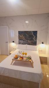 a bed with a tray of food and drinks on it at Hostal Avenida Andalucia in Seville