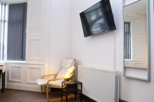 a room with a chair and a tv on a wall at Roker all ensuite Guest House in Sunderland