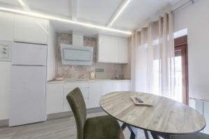 een witte keuken met een houten tafel en stoelen bij VTAR Puerta Del Sol in Villacarrillo