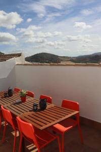 a wooden table and red chairs on a balcony at CASA ALEGRIA in Algodonales