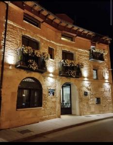 a brick building with windows and potted plants at Hotel Puerta del Arco in Tudela de Duero