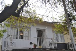 a white house with a porch and a balcony at B&M in Mendoza