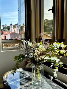 un jarrón de flores sentado en una mesa frente a una ventana en Apartamento - Riba De Sella, en Ribadesella