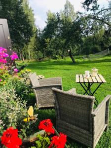 een patio met stoelen, een tafel en bloemen bij Lauku māja Sprīdīši 