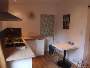 cocina con fogones y mesa. en Studio neuf - accès SPA, SAUNA et Piscine Chauffée, en Saint-Vivien