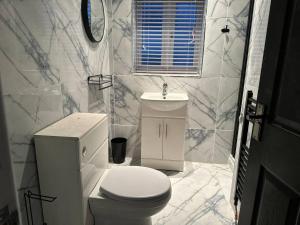 Baño blanco con aseo y lavamanos en Beautiful 2-Bed House in Bridgend en Bridgend